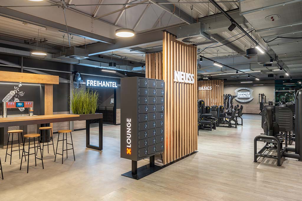 Abgetrennter Lounge-Bereich im FitX Fitnessstudio Neuss-Innenstadt mit verschiedenen Sitzmöglichkeiten. Der Bereich ist hell, freundlich und im industriellen Design gestaltet.