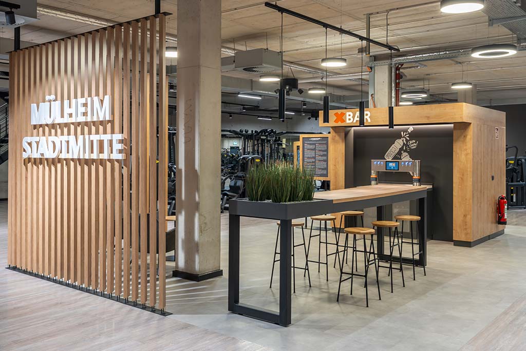 Abgetrennter Lounge-Bereich im FitX Fitnessstudio Mülheim-Stadtmitte mit verschiedenen Sitzmöglichkeiten. Der Bereich ist hell, freundlich und im industriellen Design gestaltet.