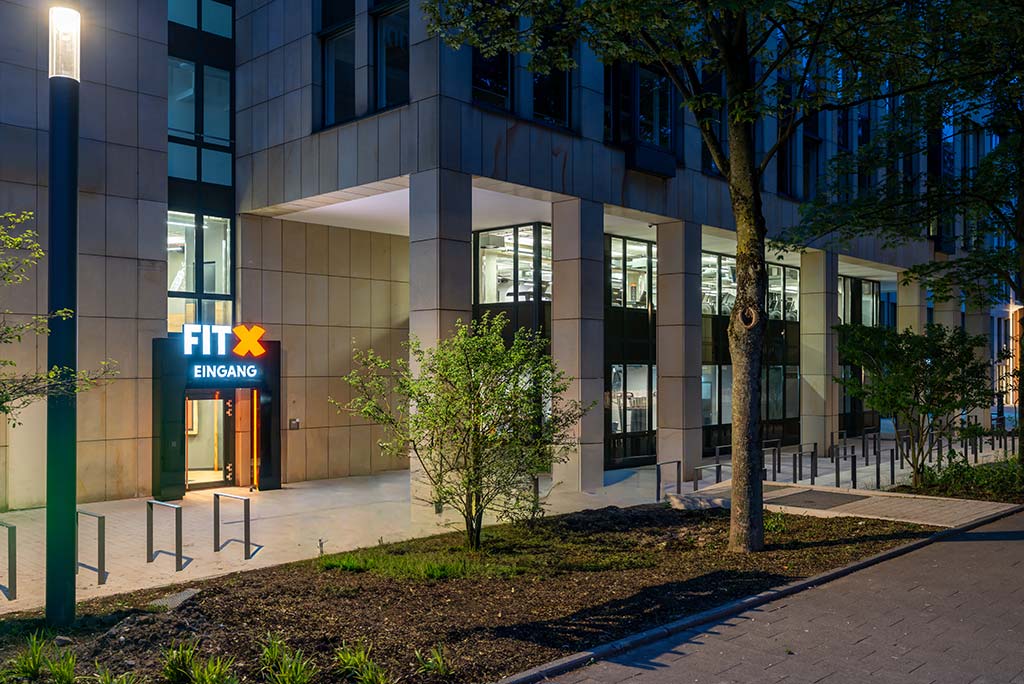 Außenansicht des FitX Fitnessstudios Düsseldorf-Derendorf. Ein großes FitX-Logo mit orangefarbenem X ist zu sehen. Das Gebäude befindet sich in einem urbanen Umfeld.