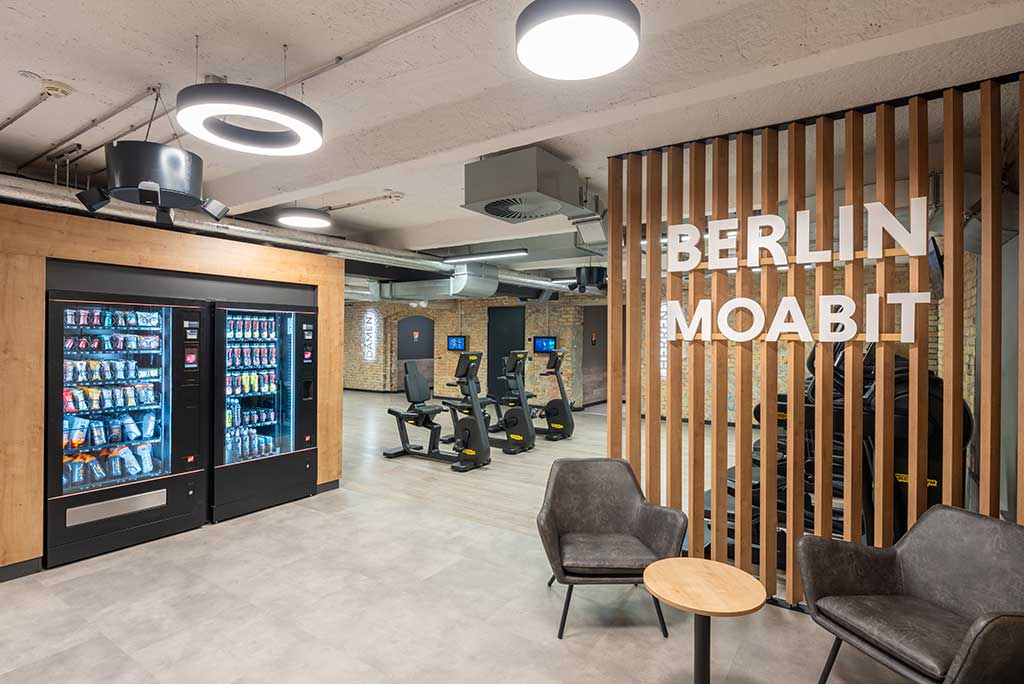 Abgetrennter Lounge-Bereich im FitX Fitnessstudio Berlin-Moabit mit verschiedenen Sitzmöglichkeiten. Der Bereich ist hell, freundlich und im industriellen Design gestaltet.