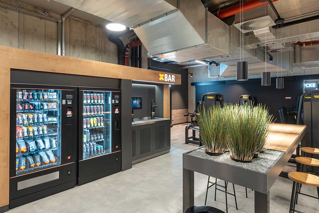 Abgetrennter Lounge-Bereich im FitX Fitnessstudio Troisdorf-Mitte mit verschiedenen Sitzmöglichkeiten. Der Bereich ist hell, freundlich und im industriellen Design gestaltet.