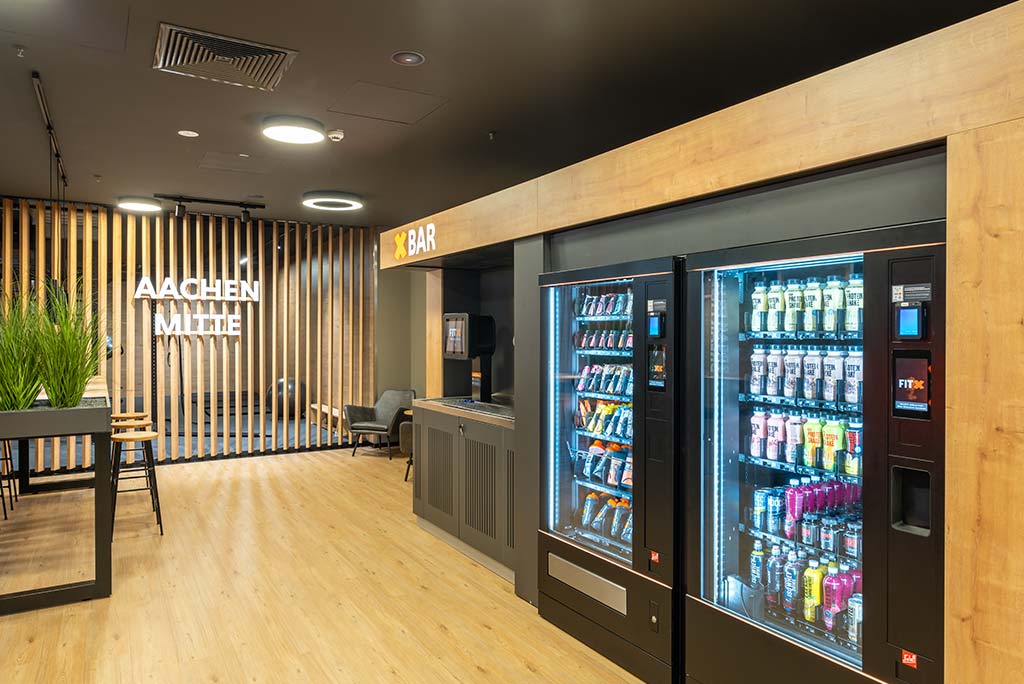 Abgetrennter Lounge-Bereich im FitX Fitnessstudio Aachen-Mitte mit verschiedenen Sitzmöglichkeiten. Der Bereich ist hell, freundlich und im industriellen Design gestaltet.