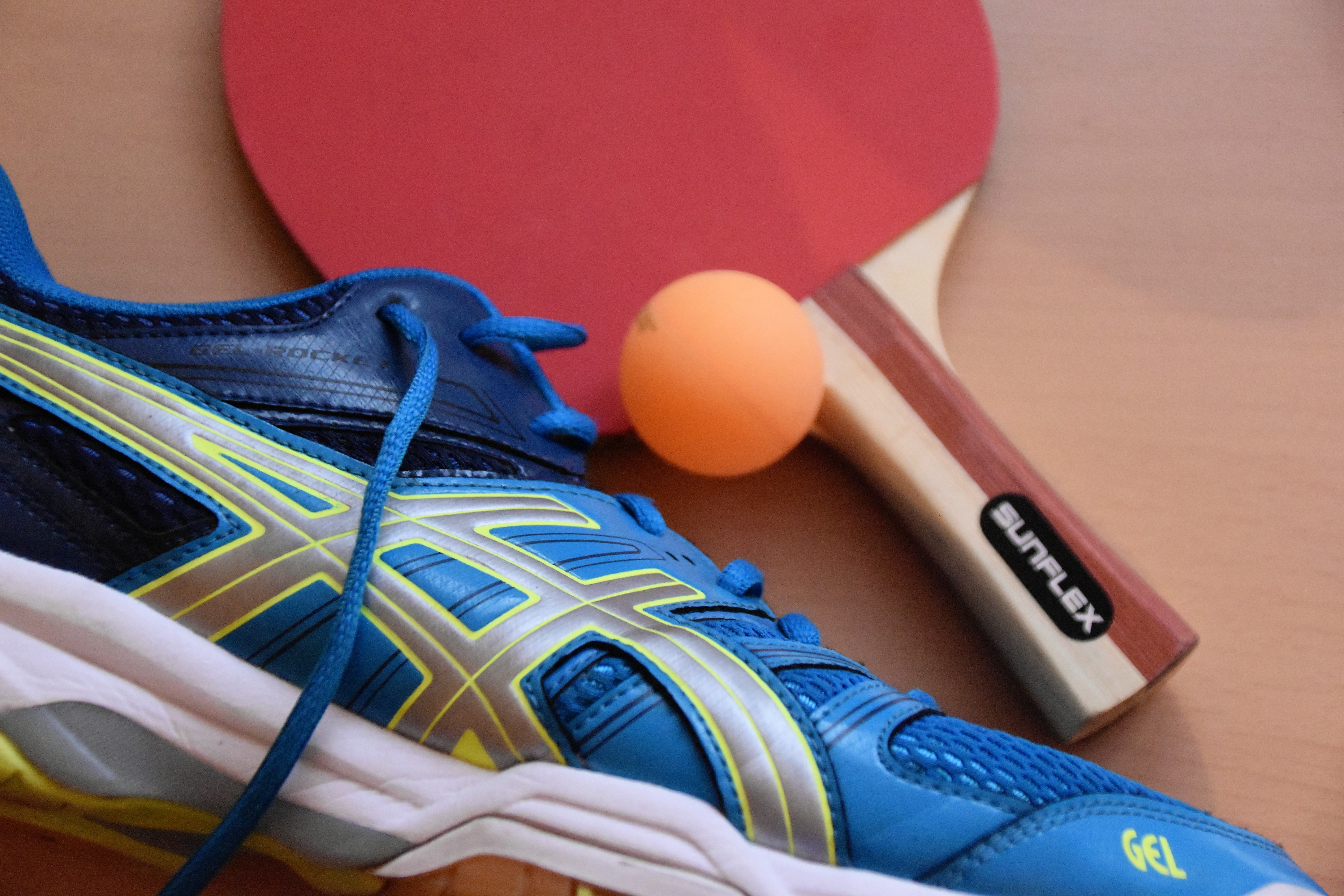 Bild: Bild eines blauen Sportschuhe, eines Tischtennisschlägers und einem Ping Pong Ball.