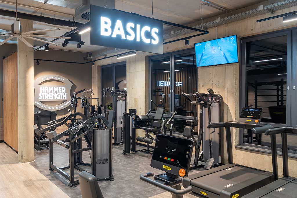 Zirkel-Bereich im FitX Fitnessstudio Troisdorf-Mitte, in dem verschiedene Trainingsgeräte kreisförmig angeordnet sind. Über den Geräten hängt ein großer Leuchtring, der in grün oder rot leuchtet und die Übungsdauer anzeigt.