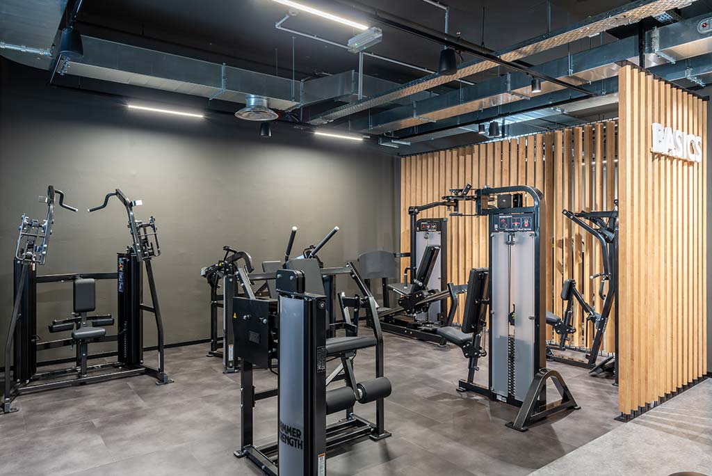 Zirkel-Bereich im FitX Fitnessstudio Aachen-Mitte, in dem verschiedene Trainingsgeräte kreisförmig angeordnet sind. Über den Geräten hängt ein großer Leuchtring, der in grün oder rot leuchtet und die Übungsdauer anzeigt.