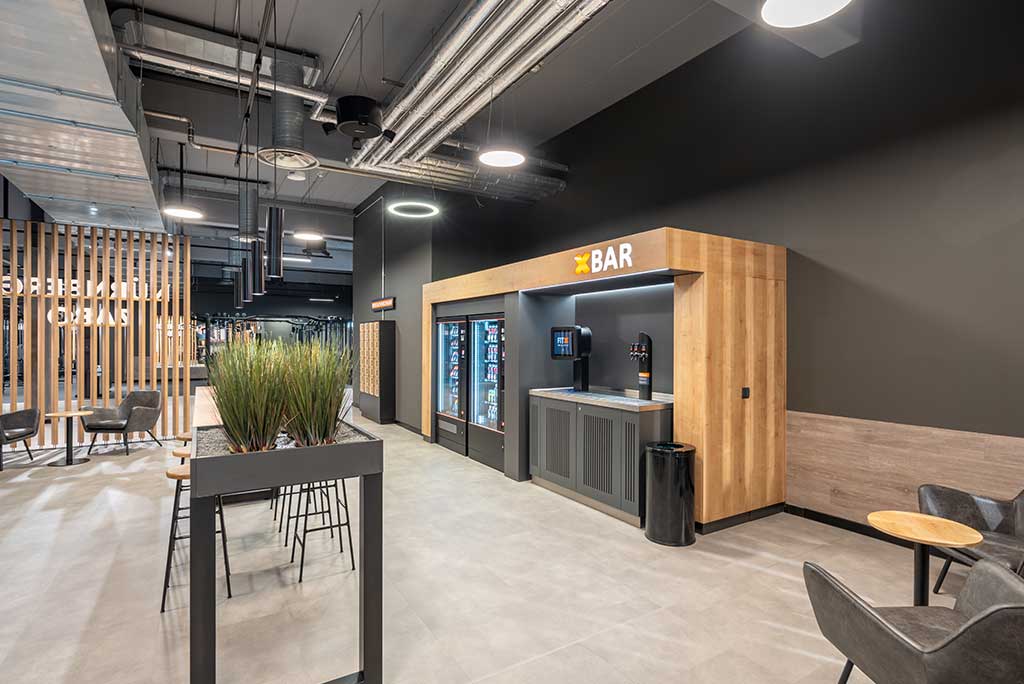 Abgetrennter Lounge-Bereich im FitX Fitnessstudio Nürnberg-Zabo mit verschiedenen Sitzmöglichkeiten. Der Bereich ist hell, freundlich und im industriellen Design gestaltet.
