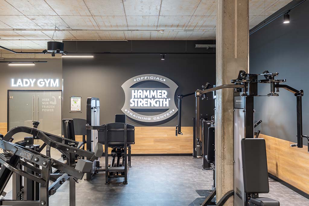 Zirkel-Bereich im FitX Fitnessstudio Essen-Bergerhausen, in dem verschiedene Trainingsgeräte kreisförmig angeordnet sind. Über den Geräten hängt ein großer Leuchtring, der in grün oder rot leuchtet und die Übungsdauer anzeigt.