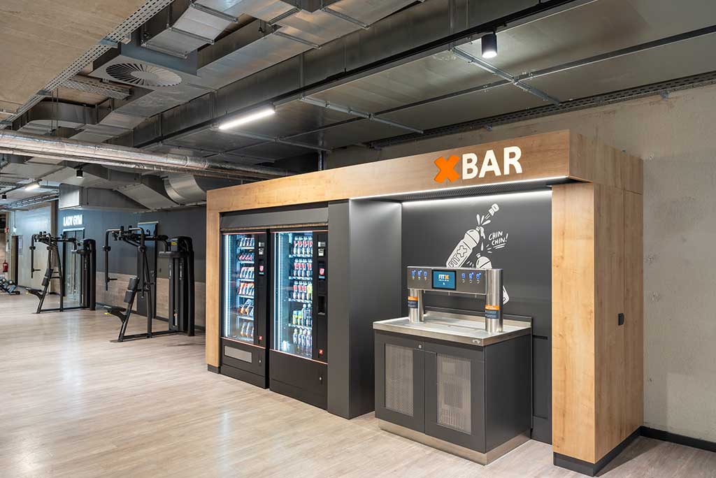 Abgetrennter Lounge-Bereich im FitX Fitnessstudio Leipzig-Neulindenau mit verschiedenen Sitzmöglichkeiten. Der Bereich ist hell, freundlich und im industriellen Design gestaltet.