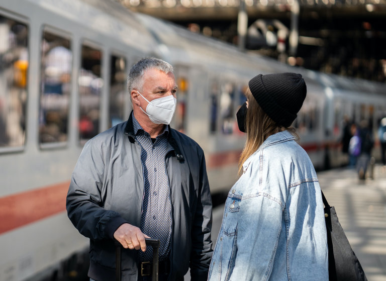 Reisende mit FFP-2 Maske vor IC im Bahnhof