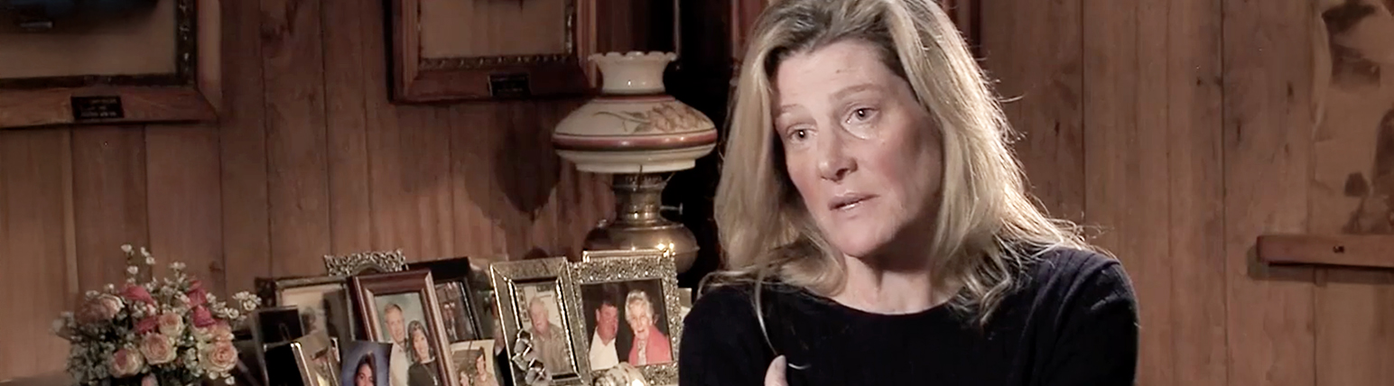 Jody sitting in a room with framed photos behind her. She is talking about her mother, Ruth, a person with Parkinson's related hallucinations and delusions.