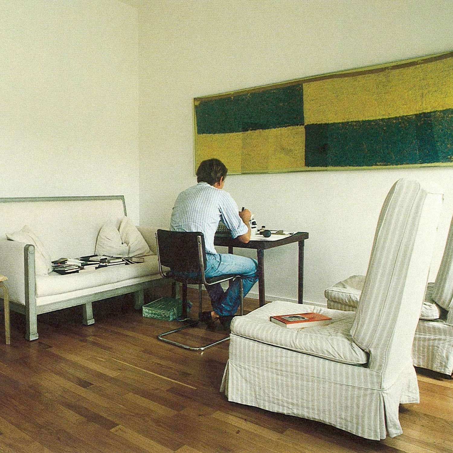 Boxy white couch and tall white chairs, with Chatwin seated in a black chair facing a black desk.