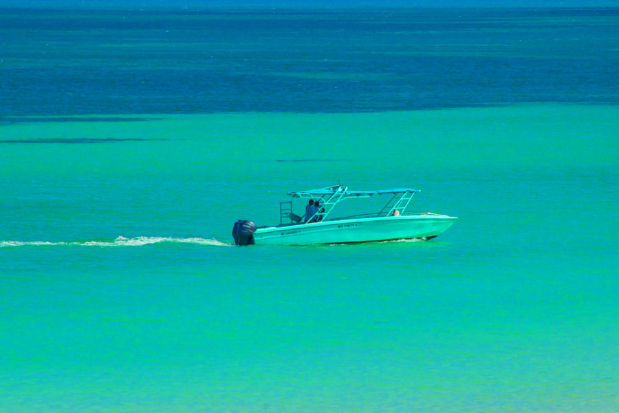 A turquoise tour boat blends in with the colourful Holbox sea