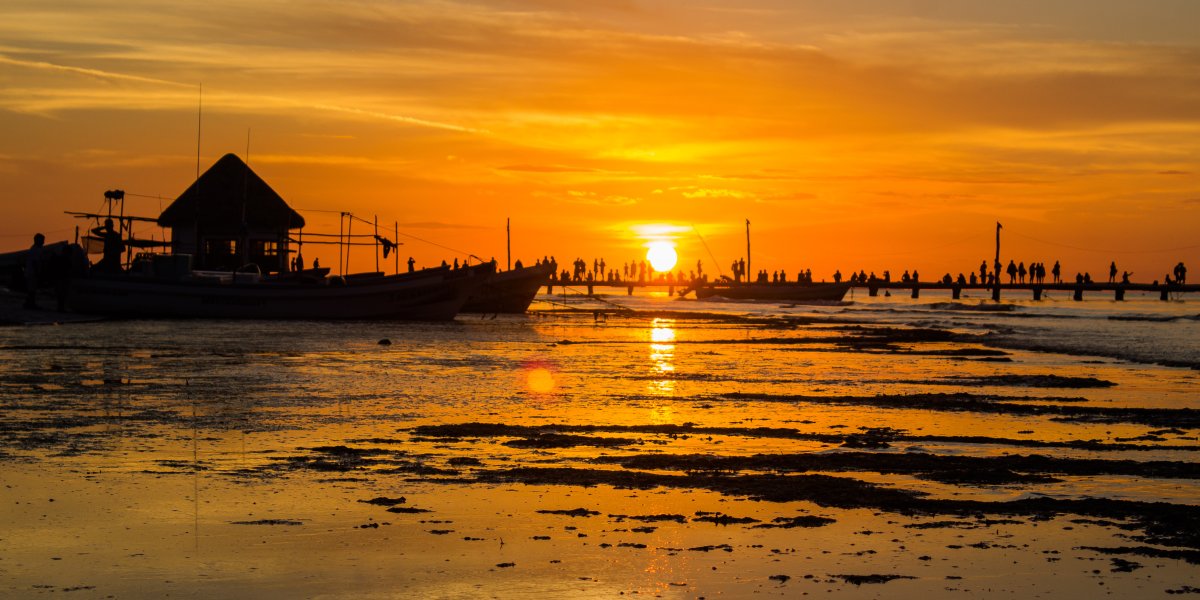 Holbox Sunset silhouettes tourists and locals on the pier with a rich orange glow