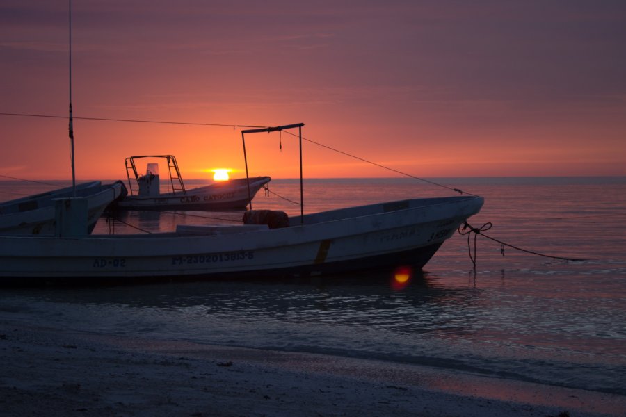 Two small fishing boats anchored on the beach of Holbox with a purple sunset