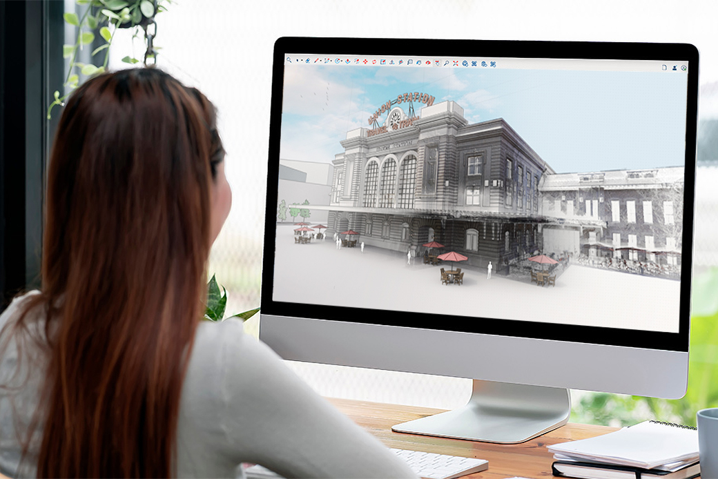 A woman views a 3D architectural model of Denver Union Station using Trimble SketchUp software on a desktop monitor.