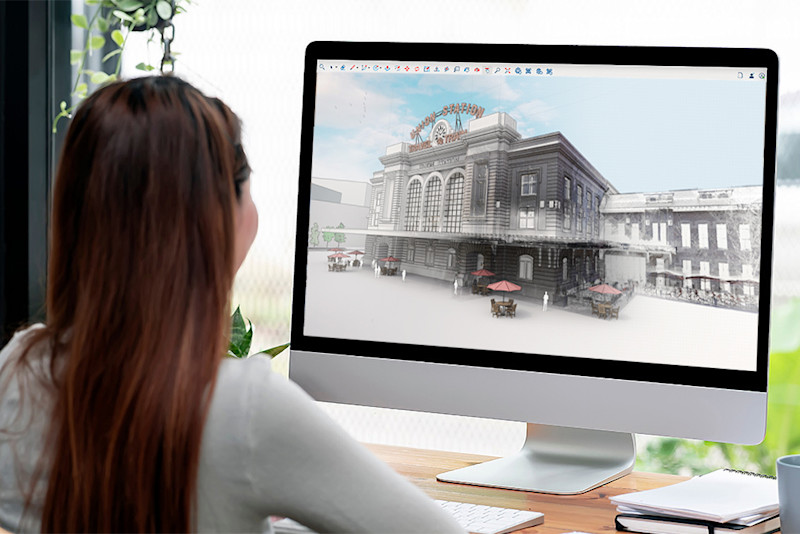 一名女子使用 Trimble SketchUp 軟體檢視桌上型螢幕上的丹佛聯合車站 3D 建築模型。