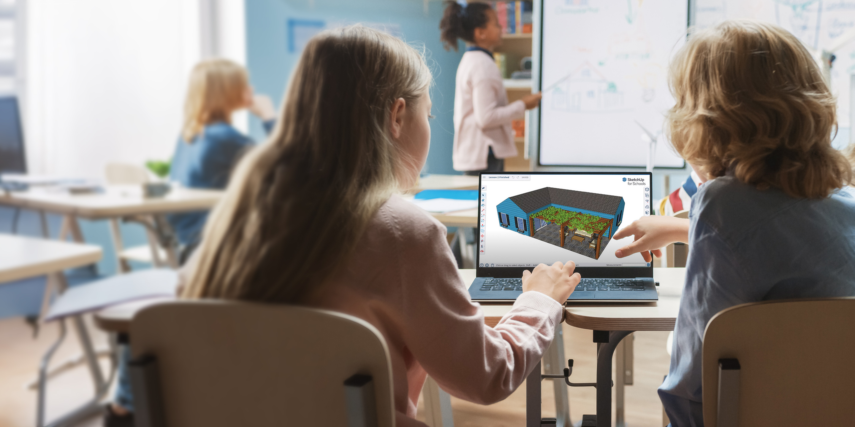 Eine Schülerin und eine Lehrerin betrachten in einem Klassenzimmer einen Laptop, auf dem in SketchUp für Schulen ein 3D-Modell angezeigt wird.