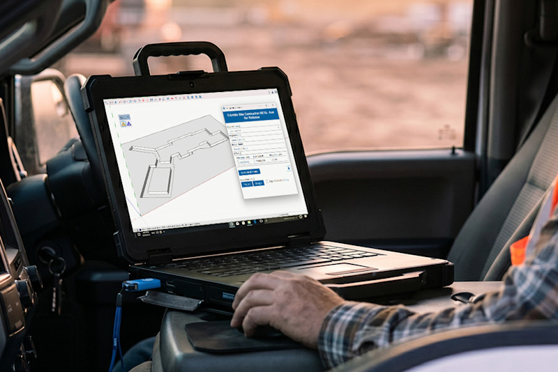 A construction worker in a truck uses a rugged Dell Latitude laptop, running Trimble Site Contractor BETA software, to analyze a 3D earthwork model for site operations.