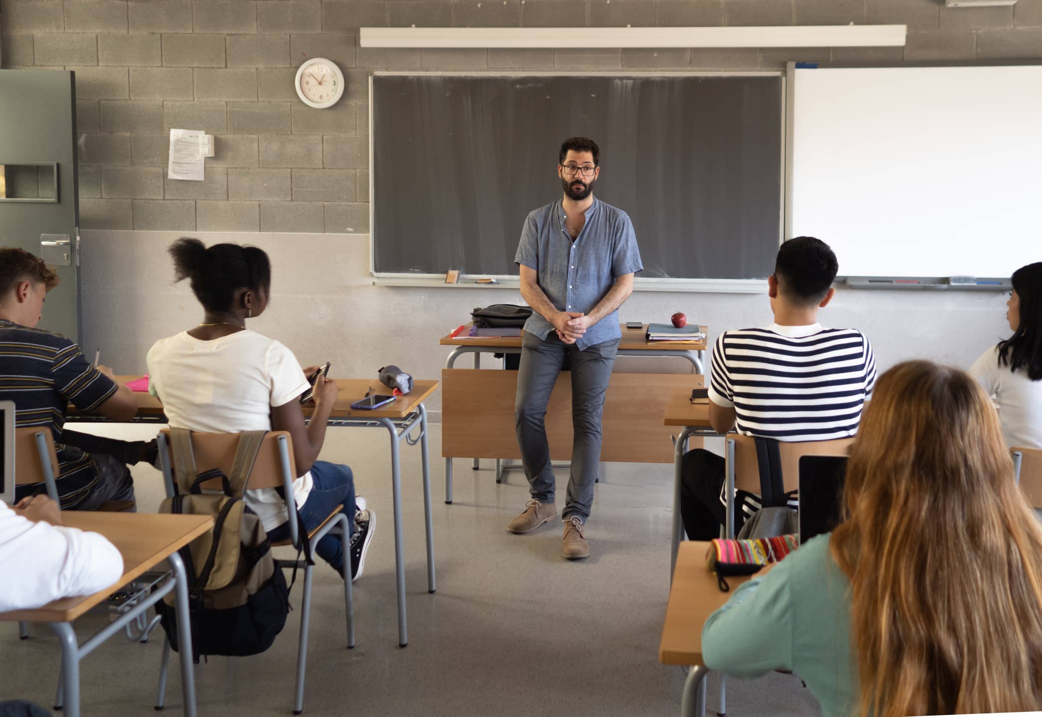 Teacher standing in front of room of students while pre-teaching writing and grammar skills