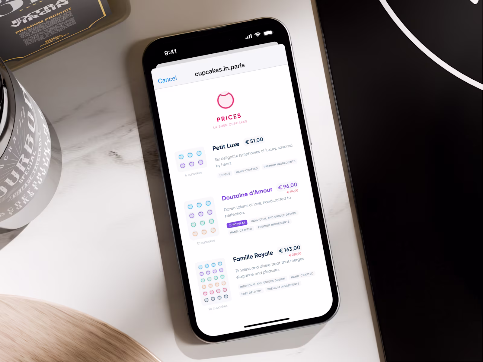 The La Shen cupcake prices page on an iPhone lying on a marble table