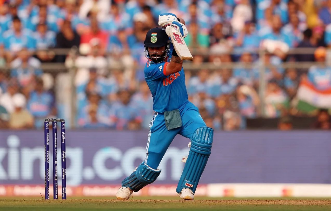 A batter mid cover drive, bat extended high, weight transferred onto the front foot