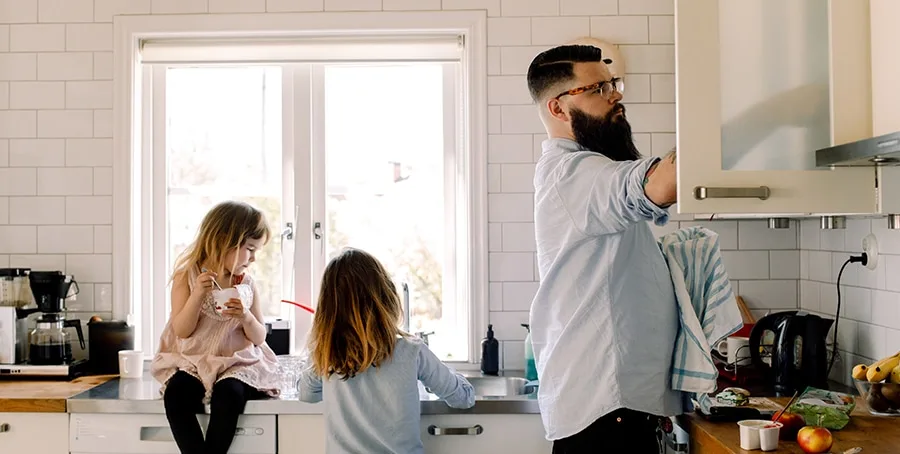 man and kids doing dishes in white kitchen