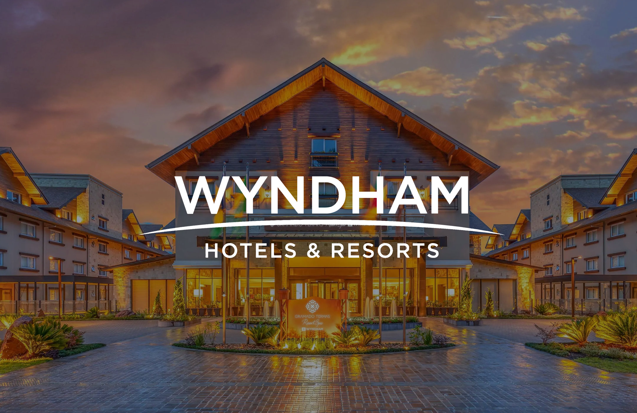 Wyndham Hotels logo overlaid on a photograph of one of their properties at sunset