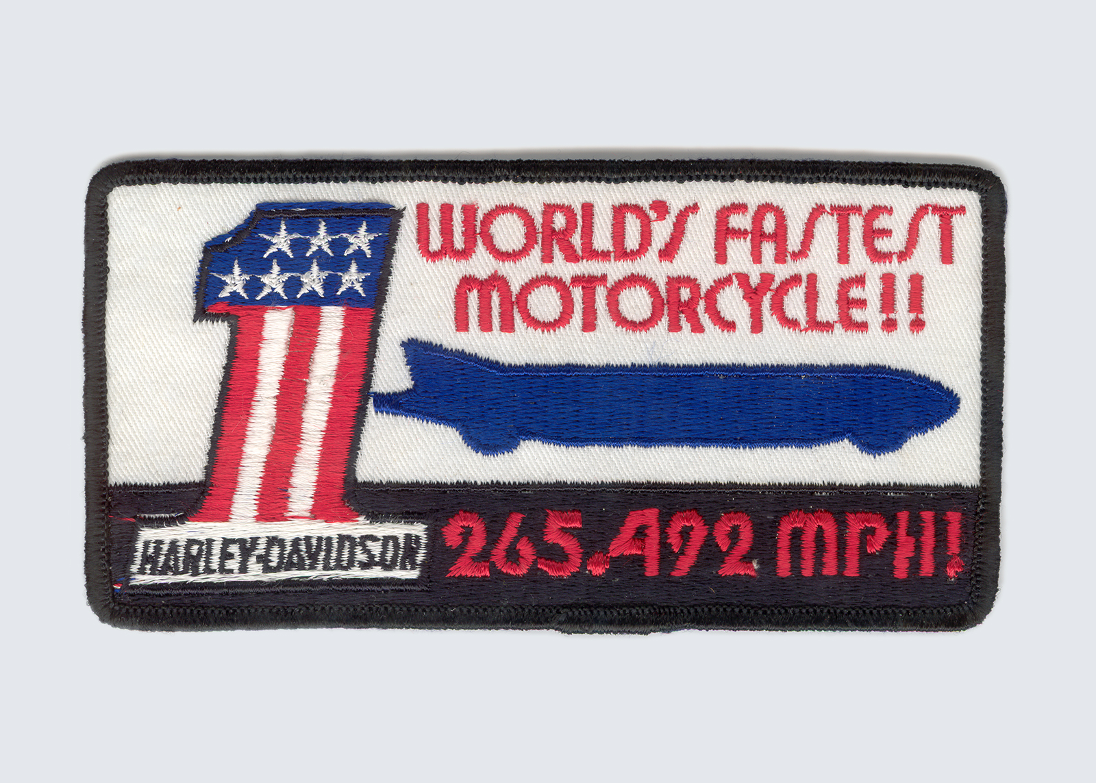 A patch showing the world’s fastest motorcycle and the Harley-Davidson One. The text on the patch reads “World’s fastest motorcycle!! 265.492 MPH!” 