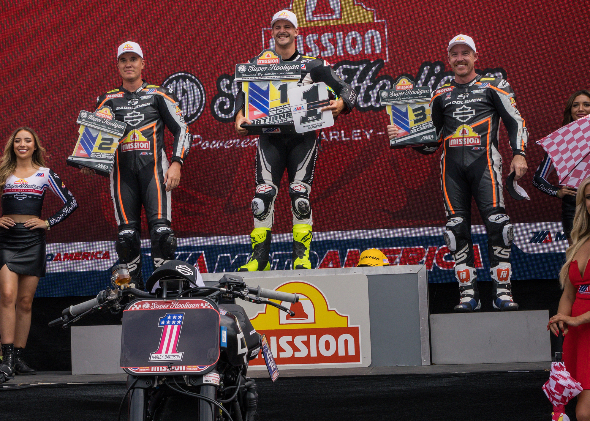 James Rispoli celebrates atop the podium holding his championship plaques alongside the 2nd and 3rd place finishers.