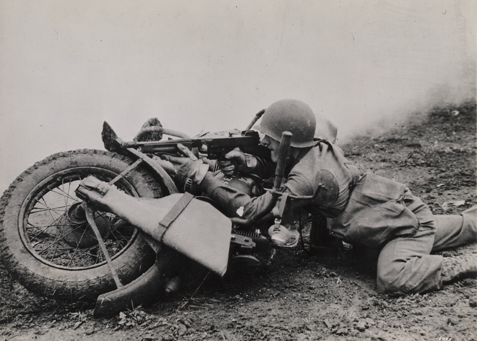 Soldier uses his motorcycle as a barrier to prop his rifle on