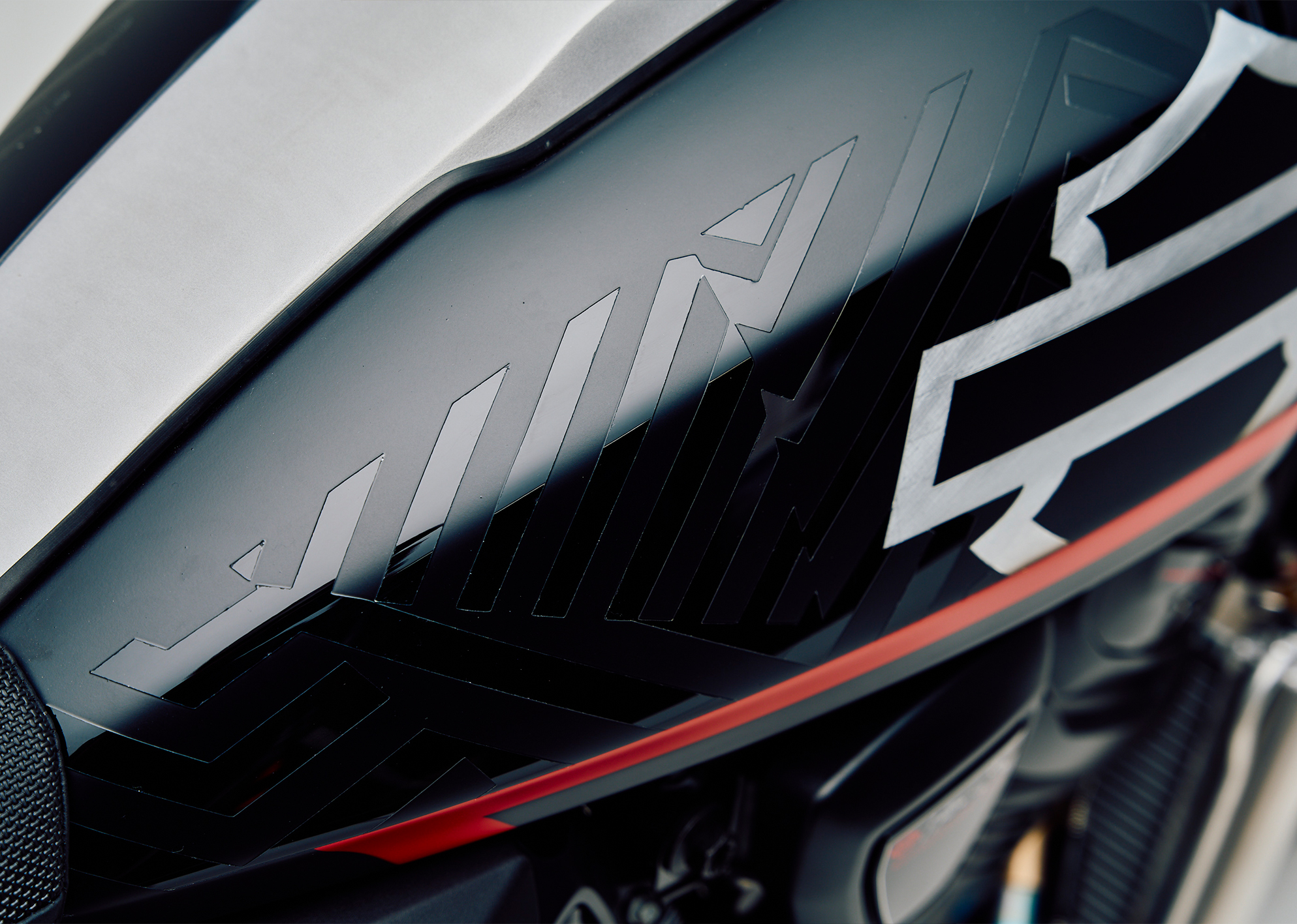 Close-up of the custom Pan America ST’s fuel tank showing a gloss dazzle pattern contrasting over matte sections with a gloss metal foiling Harley-Davidson logo.