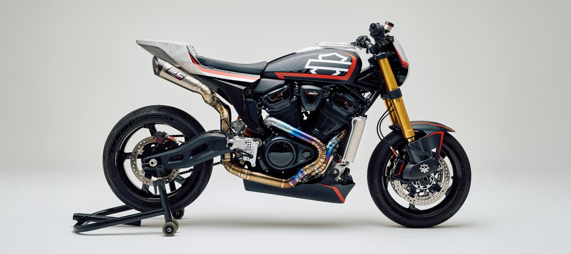 A studio photo from the side of SMCO’s custom Harley-Davidson 2025 Pan America ST with gold forks and exposed performance exhaust.