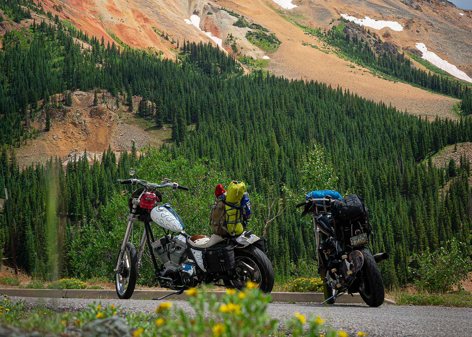 Two choppers parked at the base of a mountain 