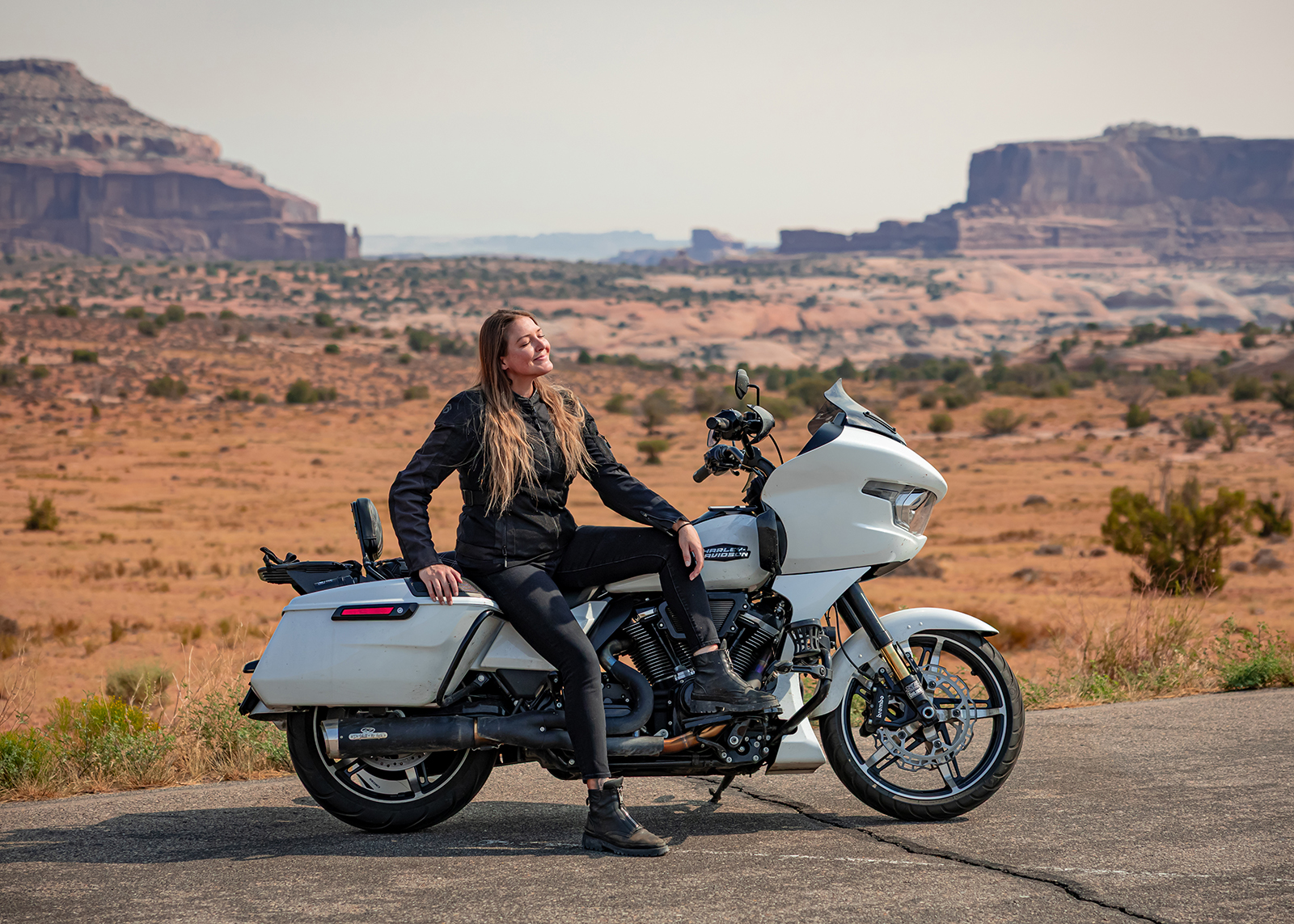 The author sits relaxed on a white Harley-Davidson Road Glide motorcycle with red rock mesas in the background.