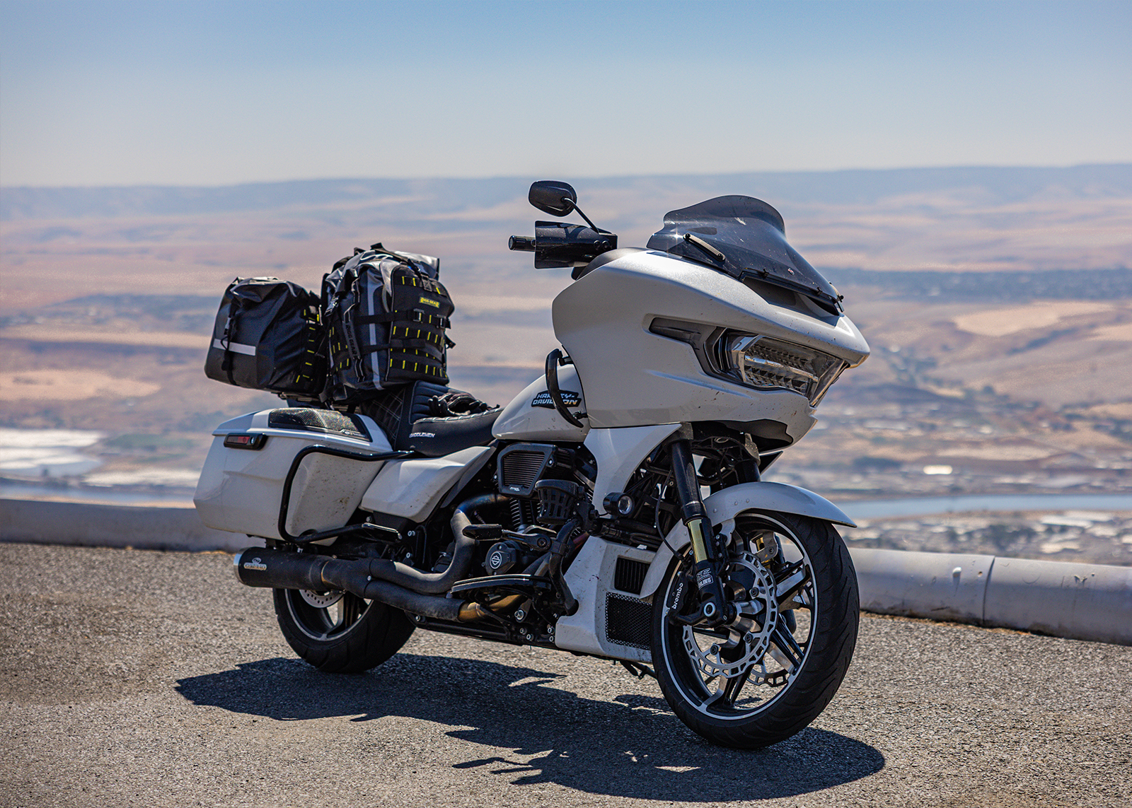 A packed white Harley-Davidson Road Glide motorcycle parked on a scenic overlook above dry hills.