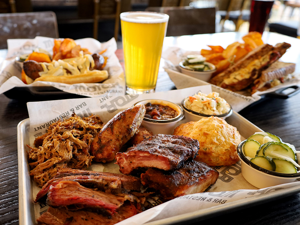 Barbecue platter with meats, sides, and a glass of beer