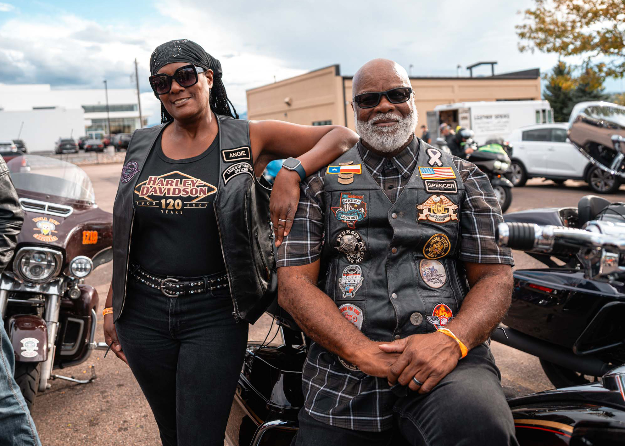 A H.O.G. member rests her arm on the shoulder of her partner as they pose for a photo with their motorcycle.