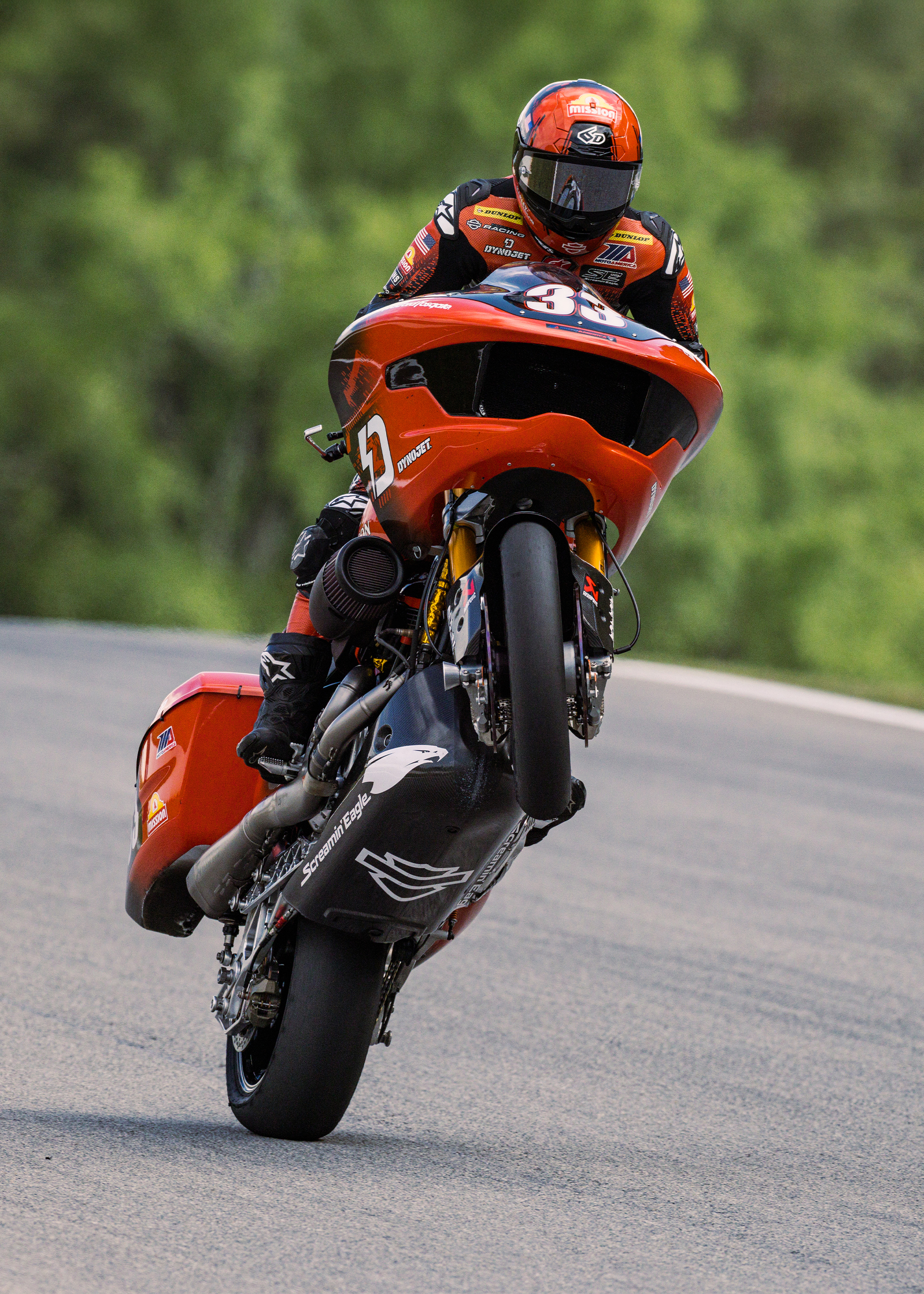 Kyle Wyman does a wheelie on his orange and black Bagger while he’s on the track. 