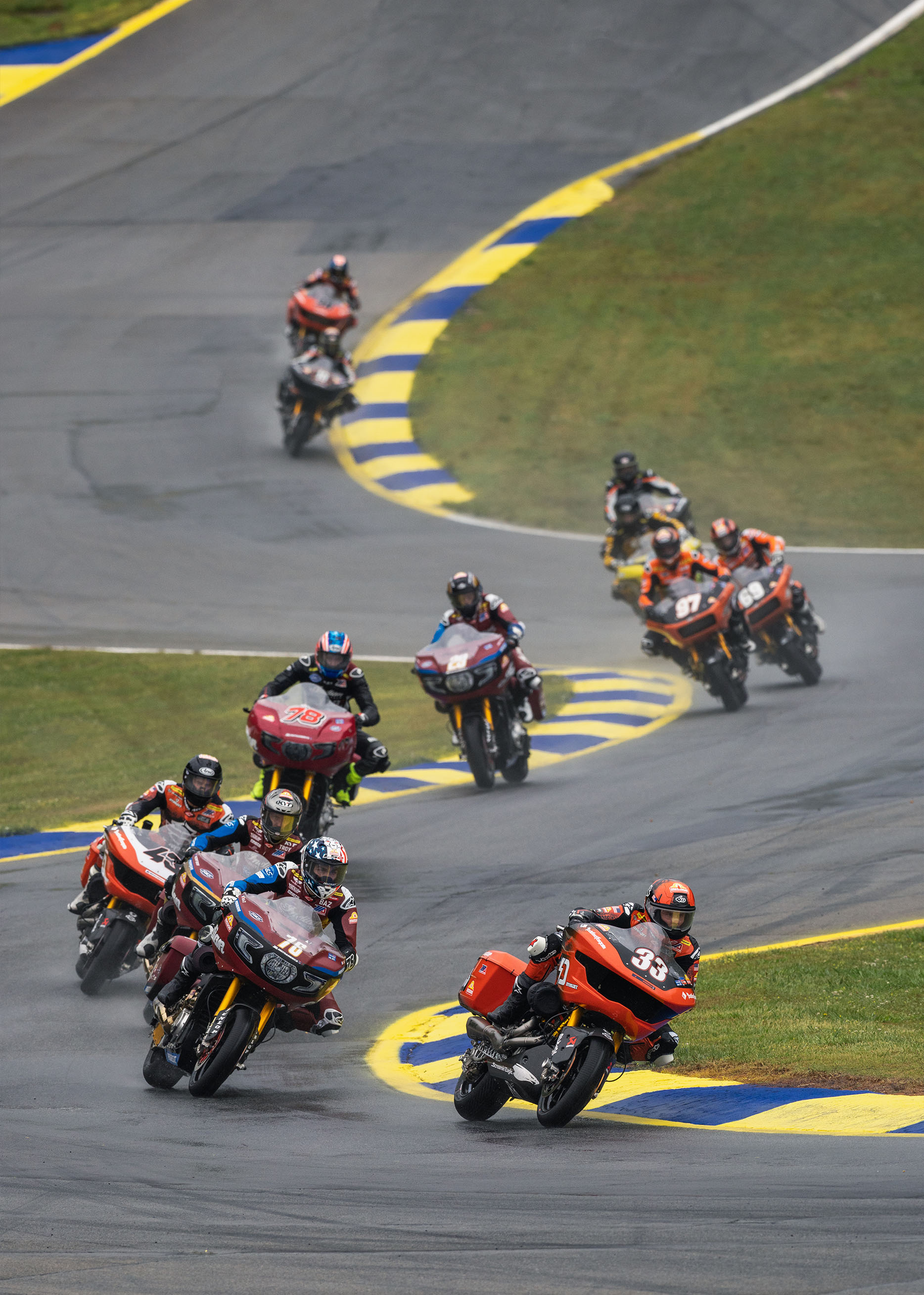 Twelve racers vying for position move through a set of curves down the track, with Kyle Wyman in the lead. 