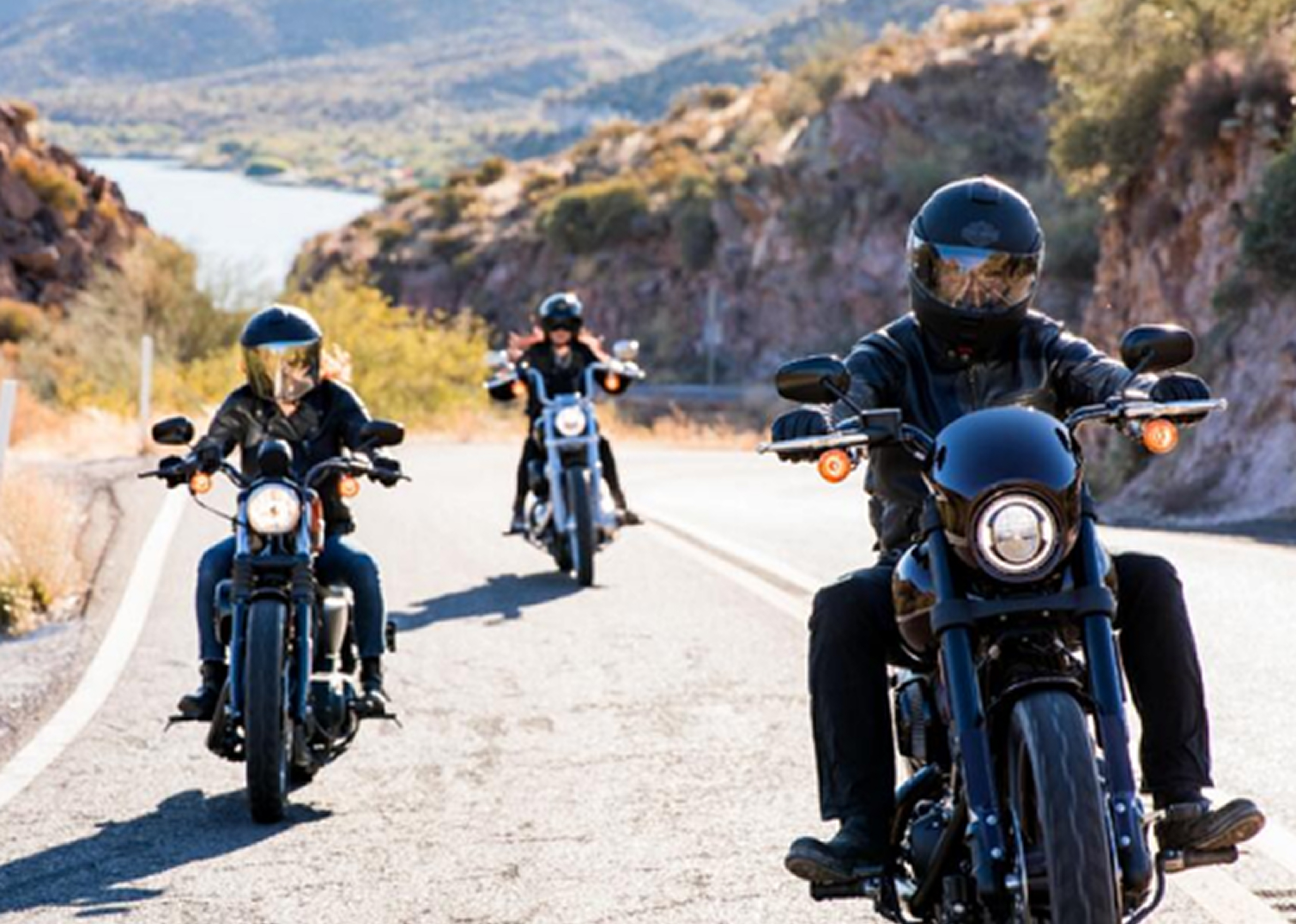 Riders riding H-D motorcycles on roads between hills