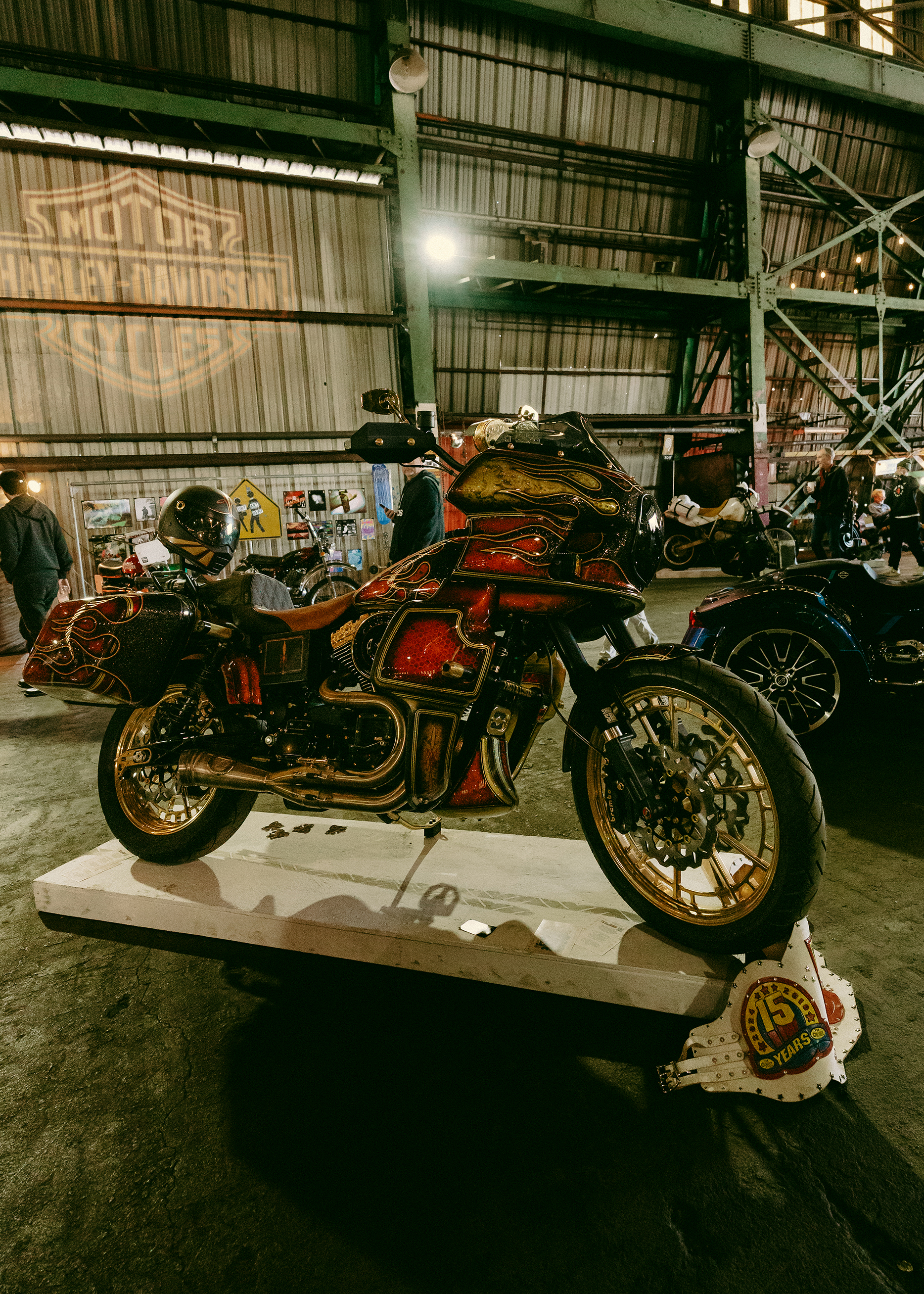A red and gold Low Rider ST with black flames sits on a stand for people to admire. 