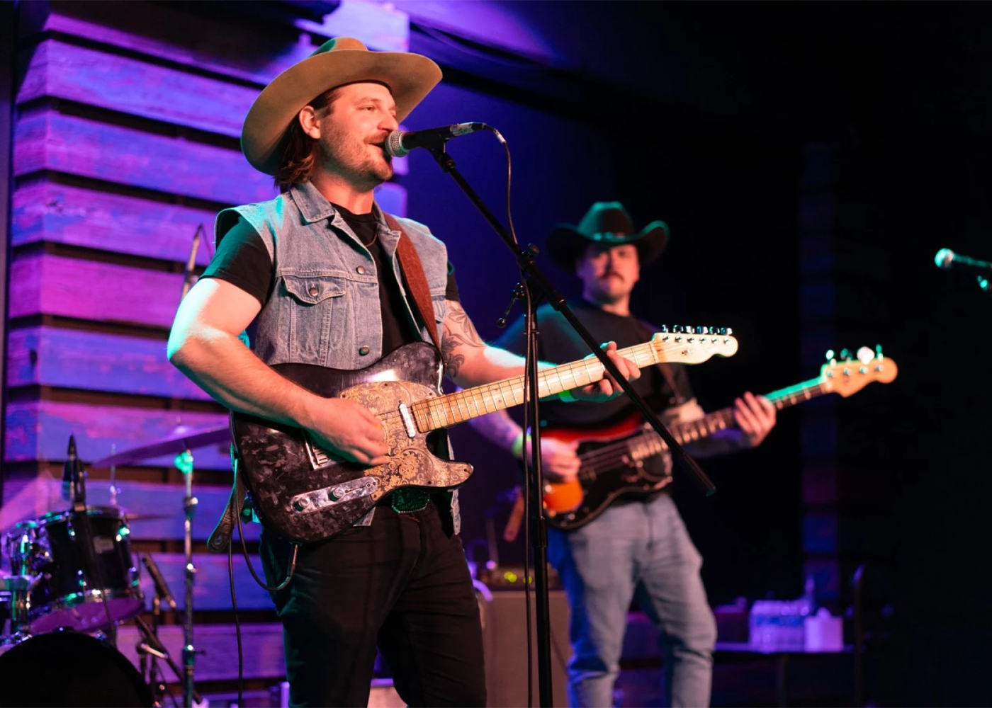 Musician playing electric guitar and singing on stage with band behind