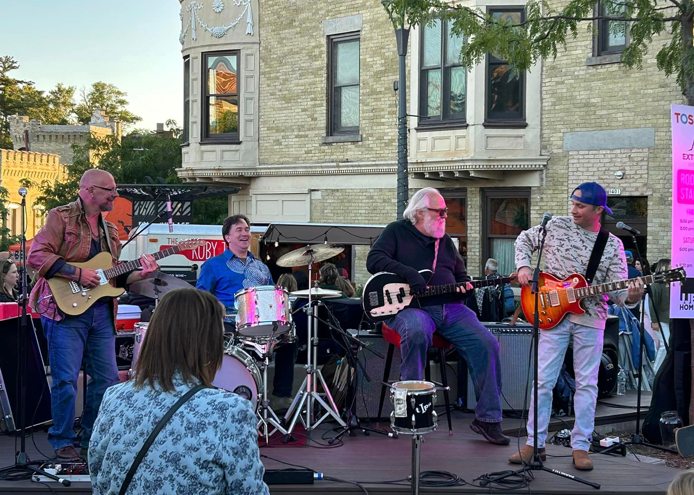 Outdoor band performing with guitars and drums in front of building