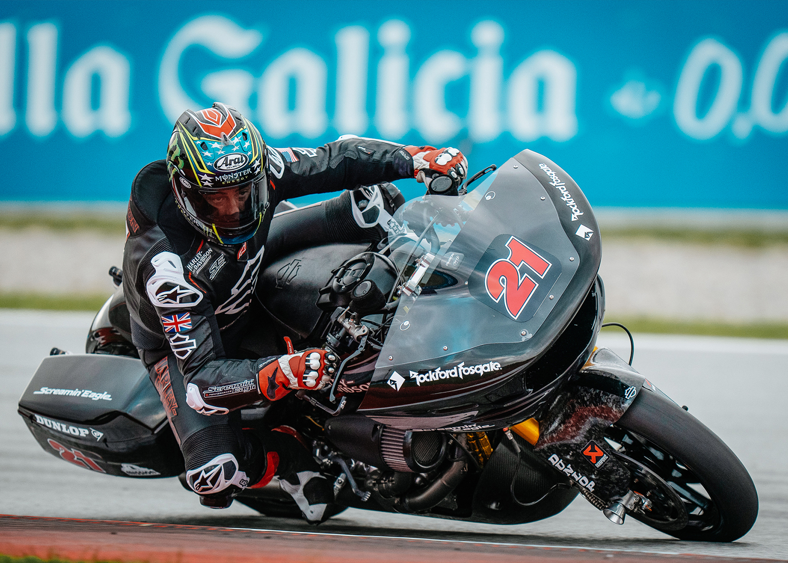 A rider in black leathers with a Union Jack on his arm leans his bike into a corner.
