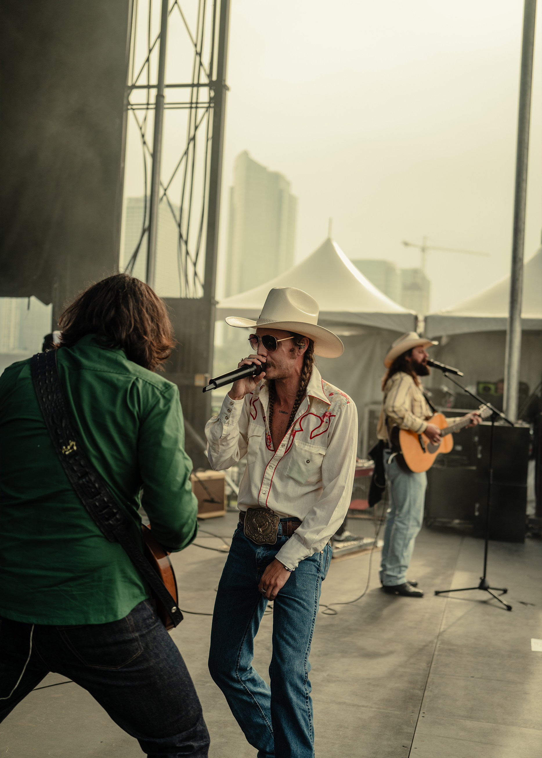 Musicians wearing country western attire perform on stage
