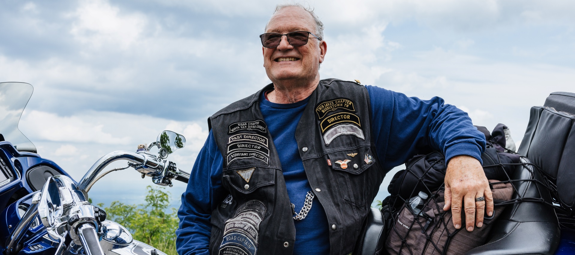Man in a HOG vest sitting on a parked motorcycle