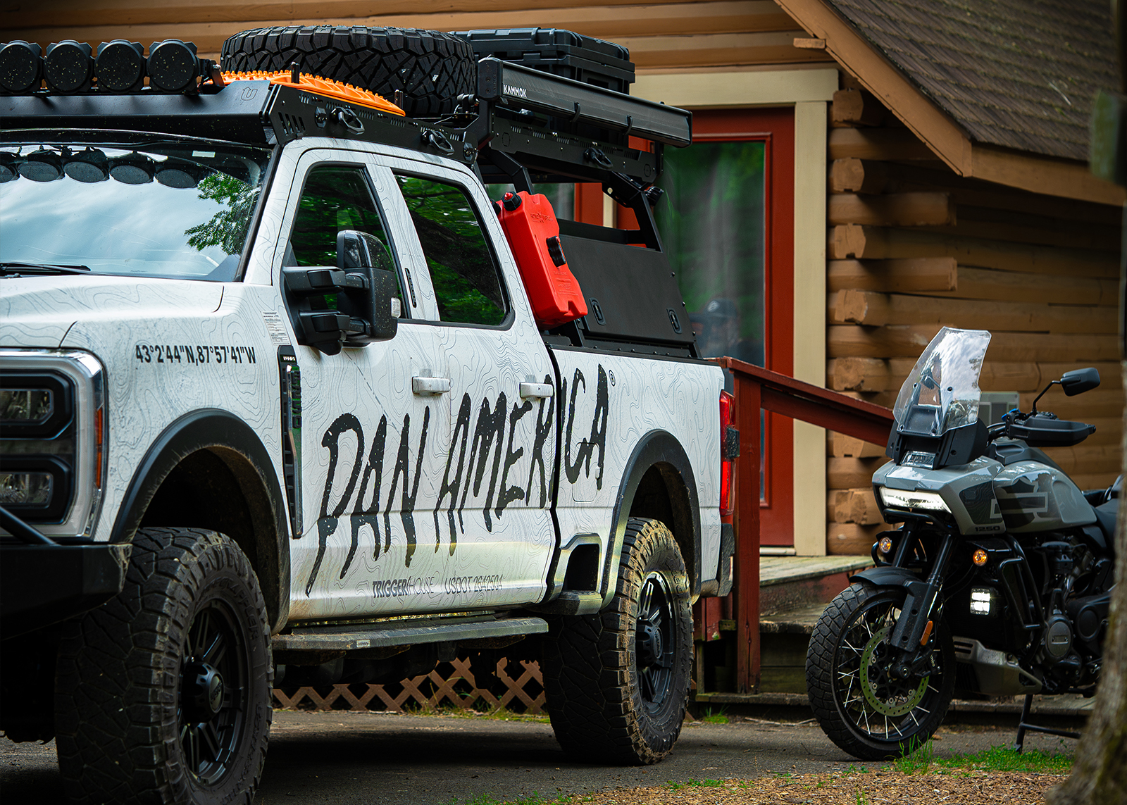 A white pickup with “Pan America” painted on the side is parked next to a gray Pan America. 