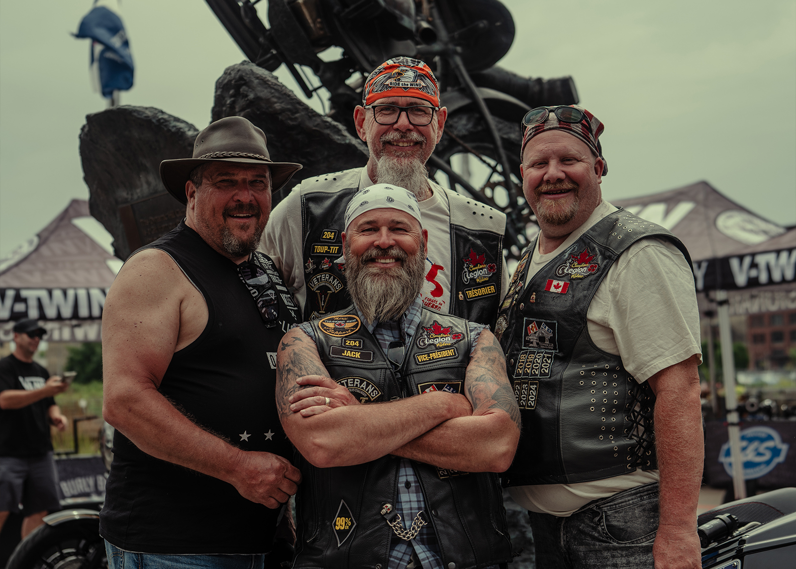 4 motorcycle riders pose for a photo in front of a statue