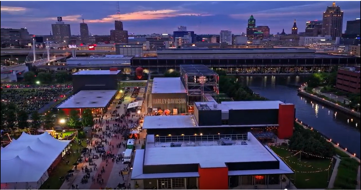 Toma aérea del campus del Museo Harley-Davidson con el horizonte de Milwaukee y el río al atardecer