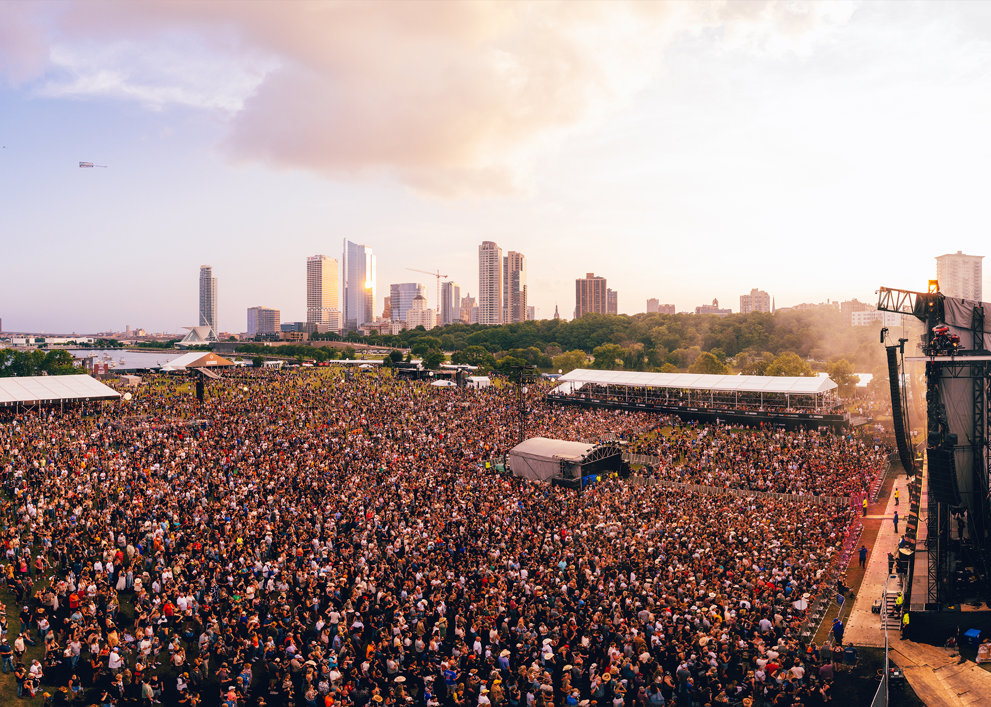 Aerial view of a large crowd at an outdoor venue with the Milwaukee skyline in the background for Harley-Davidson Homecoming 2025